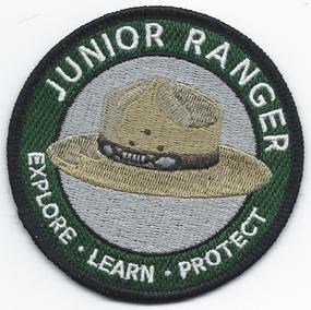 National Junior Ranger Patch 2012 showing a National Park Ranger Hat with the words Junior Ranger at the top of patch and Explore * Learn * Protect at the bottom of patch