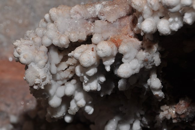 Rounded calcite formations resembling popcorn sit along a cave wall.