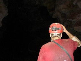 A cave explorer looks into a large, dark passage