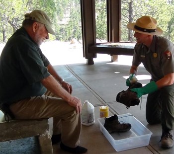 A park ranger helps a visitor to decontaminate his shoes before entering Jewel Cave. A park ranger helps a visitor to decontaminate his shoes before entering Jewel Cave.