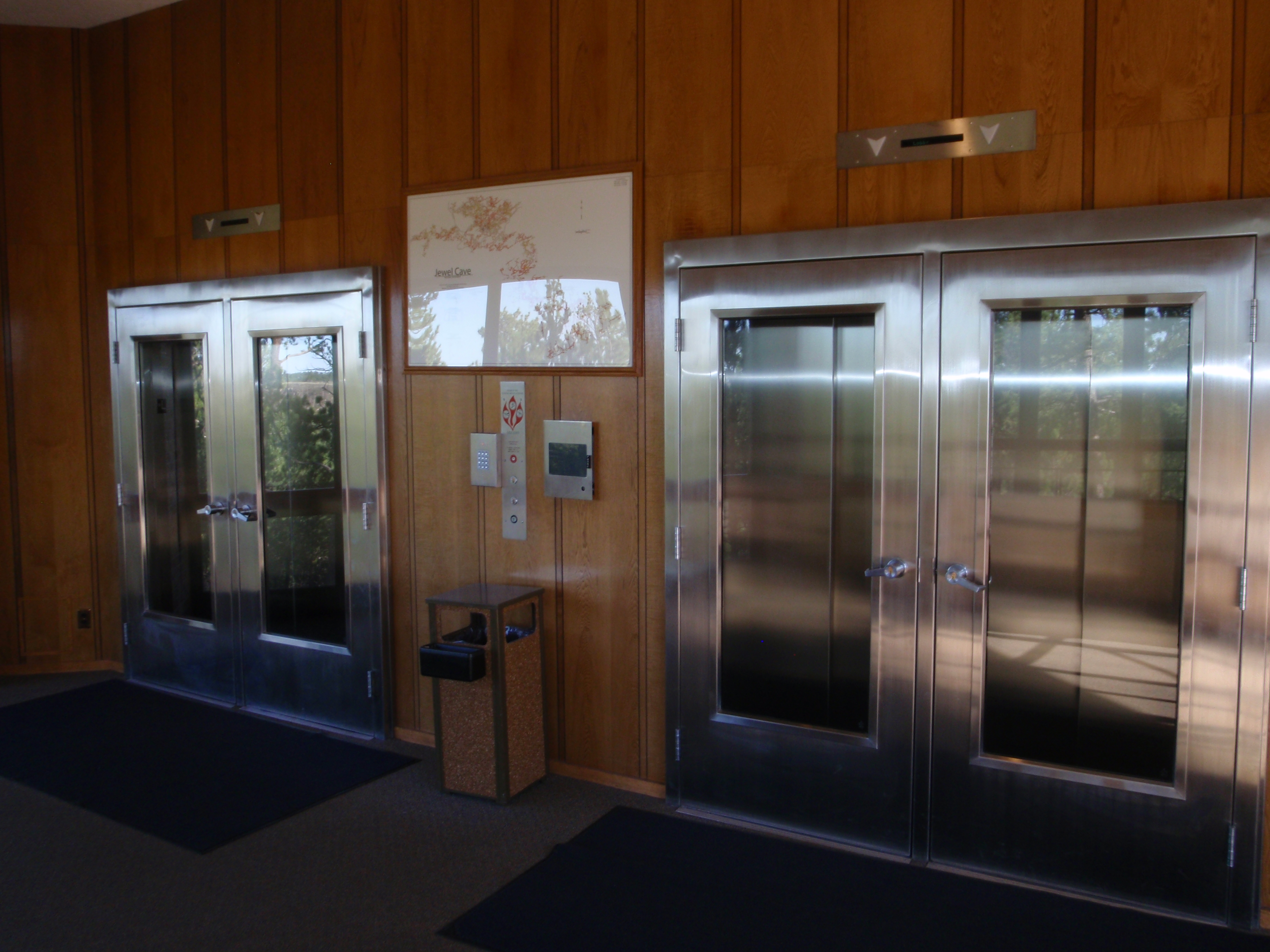 Two silver-colored sets of elevator doors with large glass fronts.