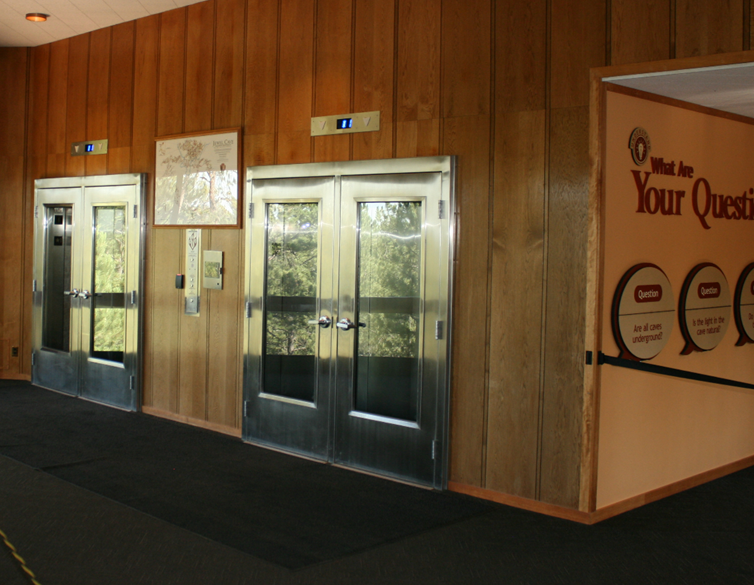 Jewel Cave Elevator Lobby Two sets of silver doors in a lobby with signage around the corner.