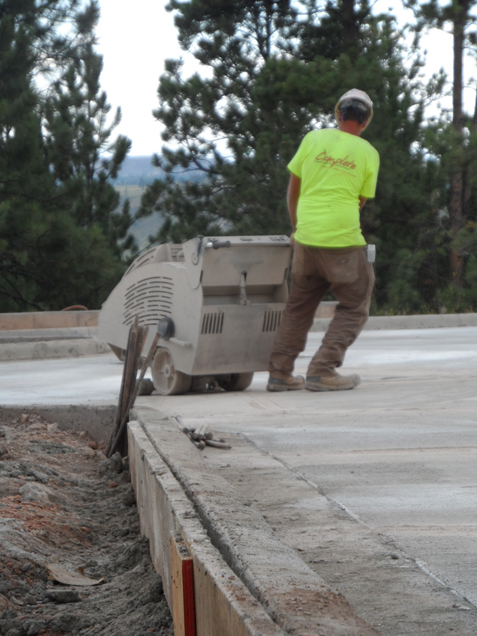 Construction staff use wet saws to cut expansion joints into the parking lot concrete.