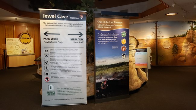 A large, gray-colored upright banner shows directional guidance for visitors entering the visitor center.