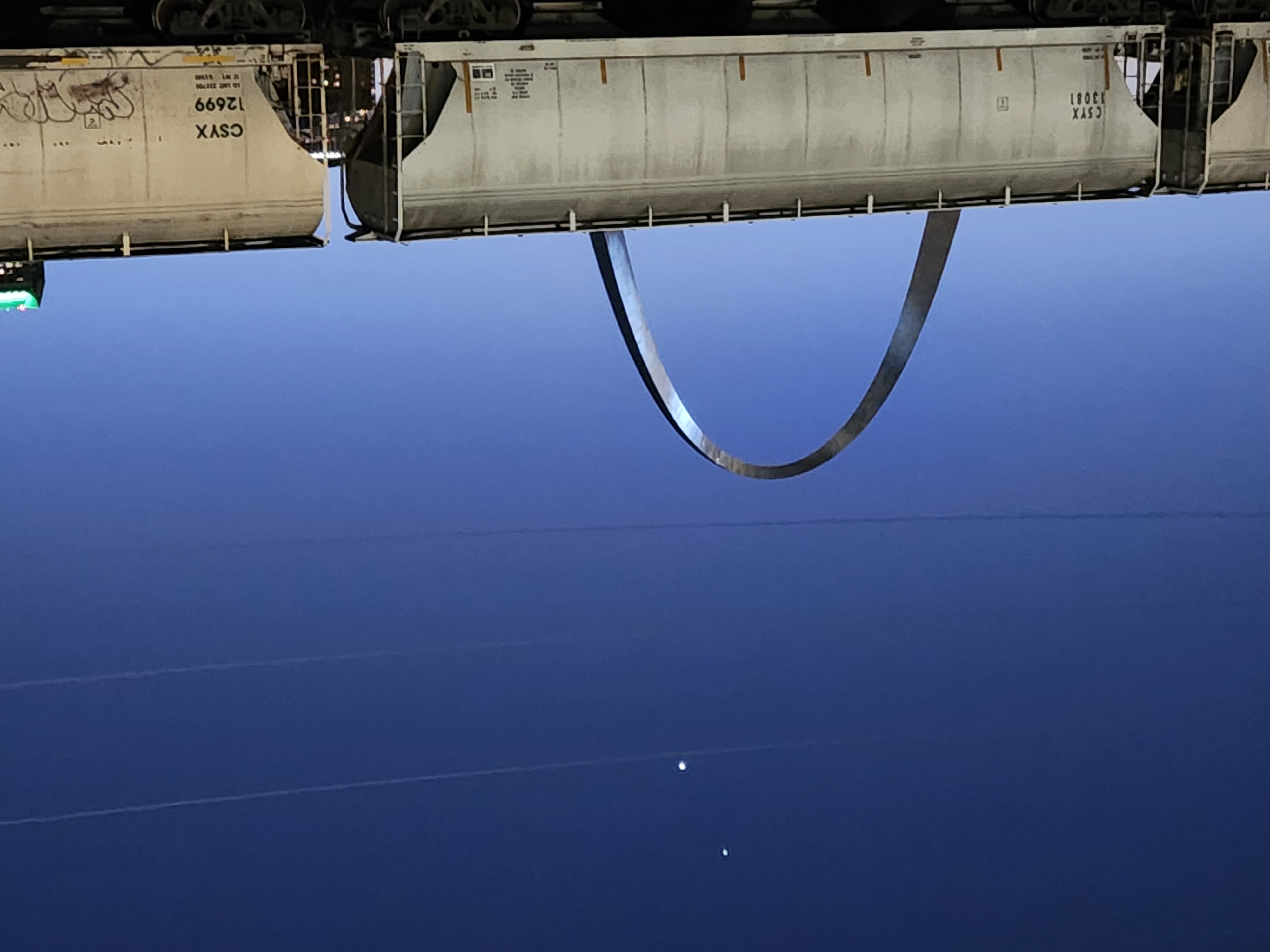 Picture of the Gateway Arch, with a blue sky background and two dots, depicting Venus and Jupiter in the sky. 