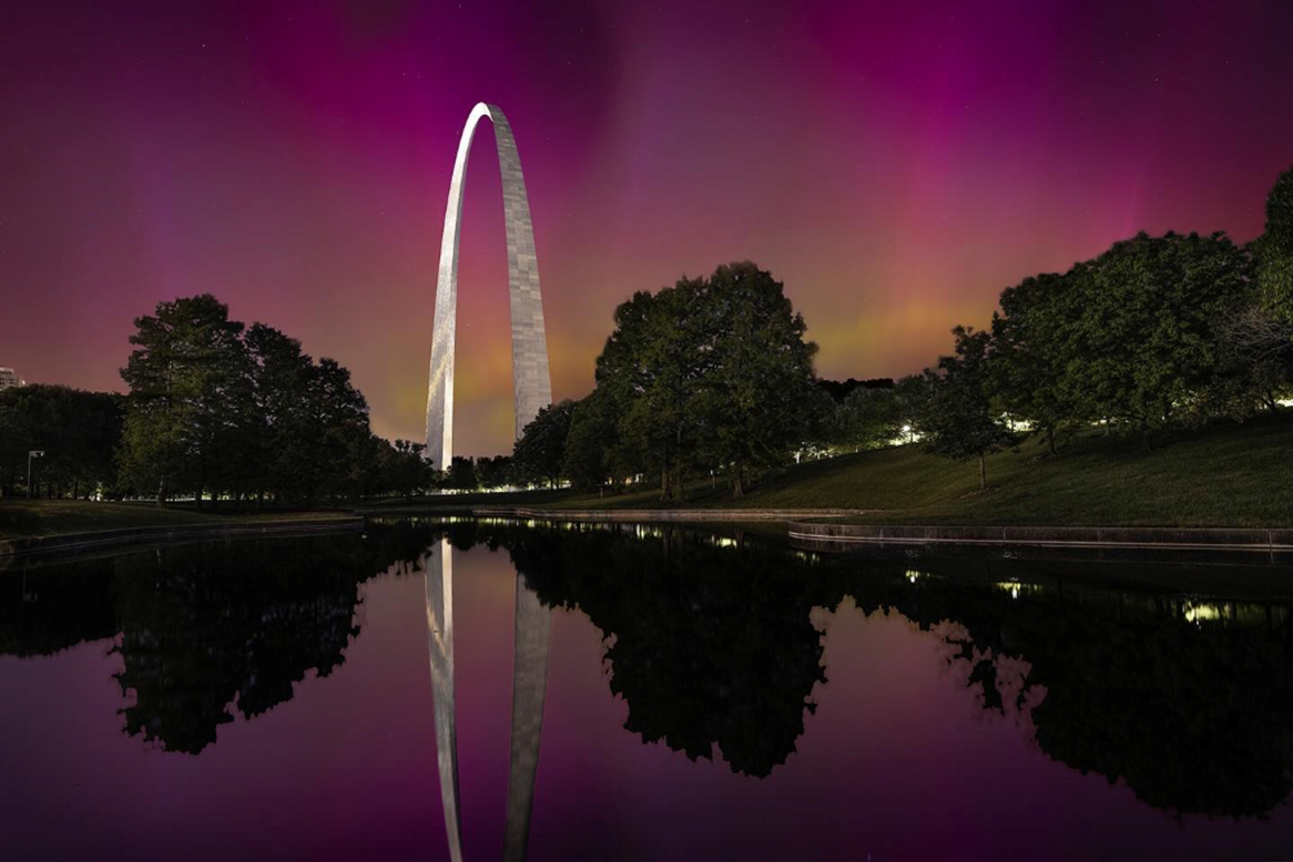 Northern Lights, South Reflecting Pool, Gateway Arch A silver-white arch, with a pink sky, reflected in water.