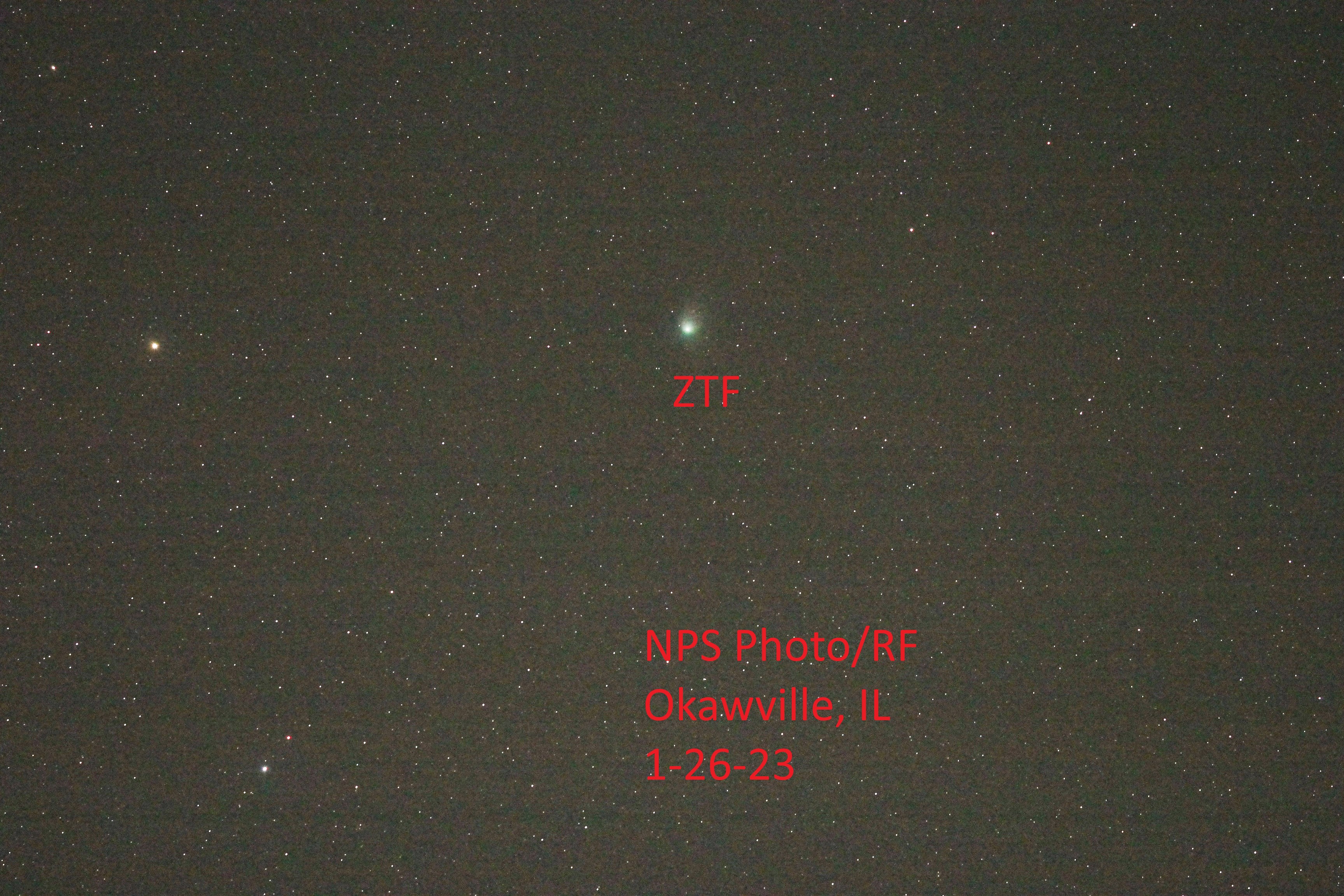 Close up of Comet ZTF White spots on a ark background, with red writing.