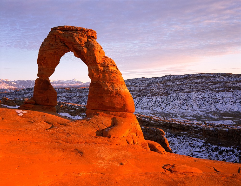 An orange Arch amid a background of the sky and a hill