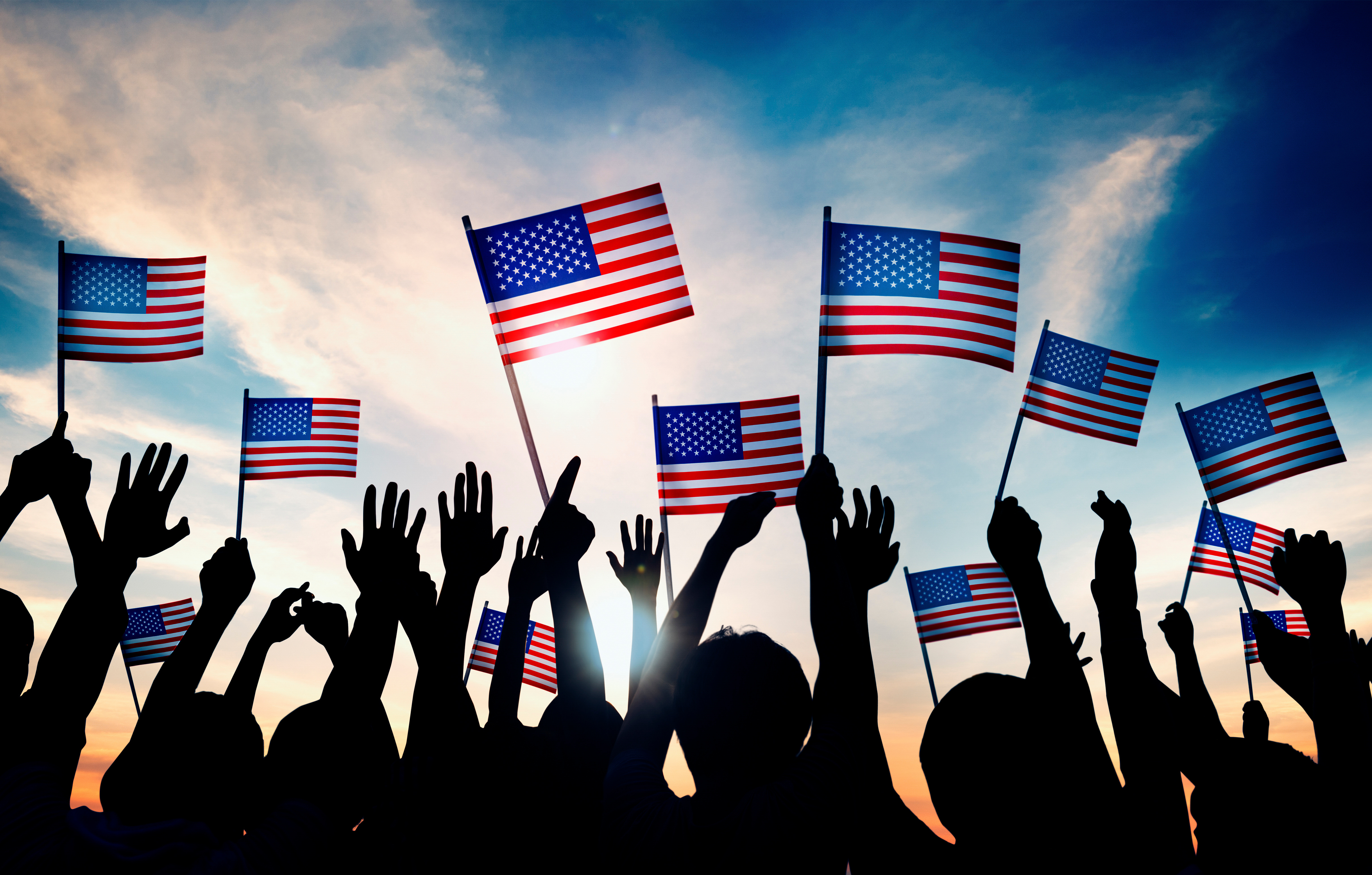 Waving US flags Arms waving small US flags, sky in the background