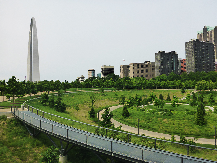 Gateway Arch in the left background, green space of the North Gateway and curving raised walkway in the foreground.