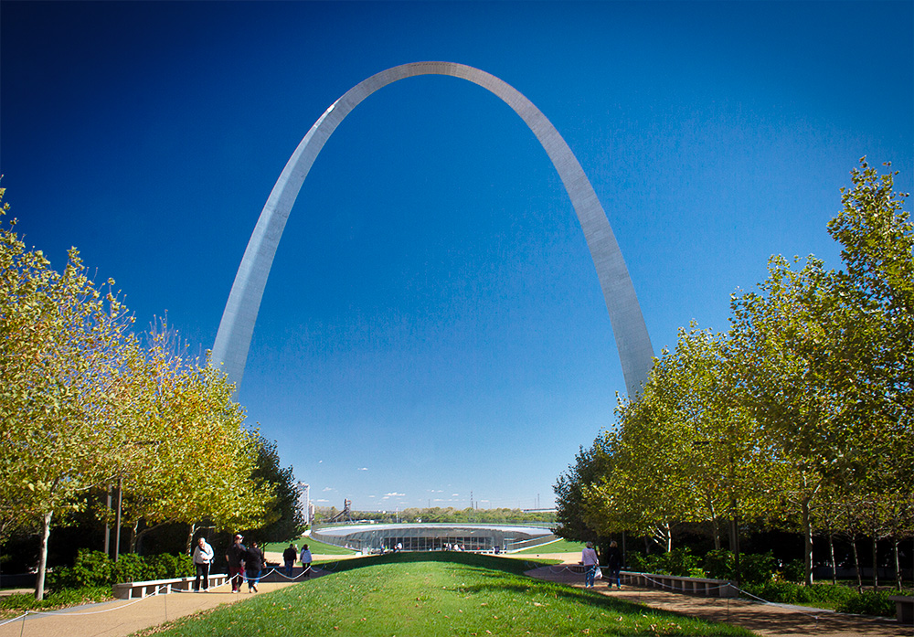 Gateway Arch with blue sky and yellow trees along the walkways