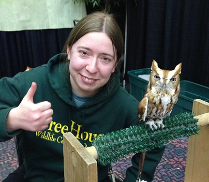 Young women giving the thumbs up posed next to a live owl