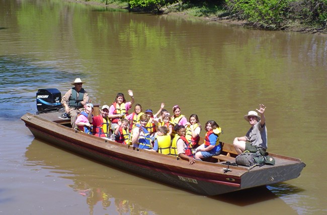Image of park ranger and visitors in an open boat on the bayou Image of park ranger and visitors in an open boat on the bayou