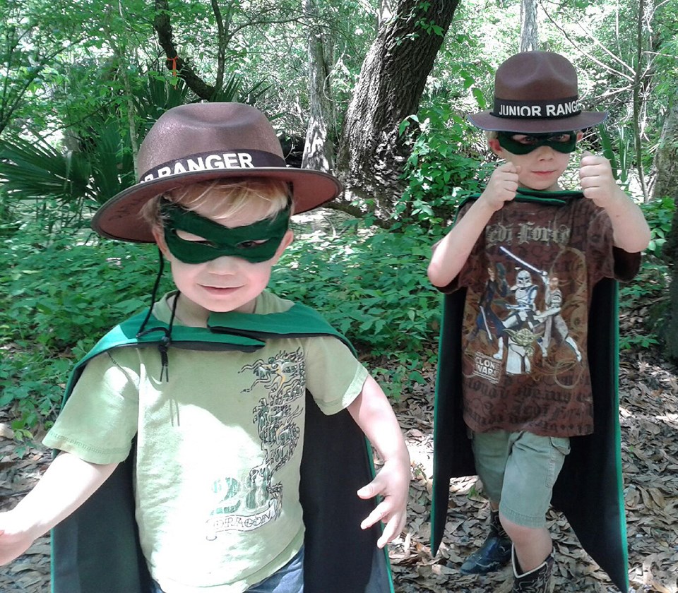 Two little boys wearing Junior Ranger hats and superhero capes