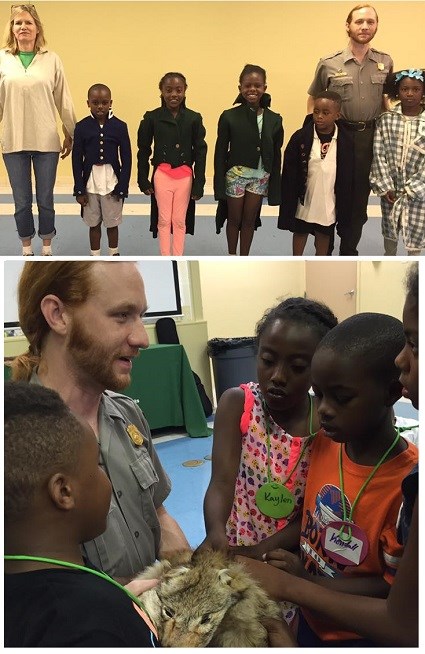 A park ranger stands with children dressed in historical tailcoats, and children examine a coyote pelt held by a park ranger