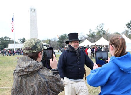 Image of students with digital tablets taking pictures of man dressed as War of 1812 sailor