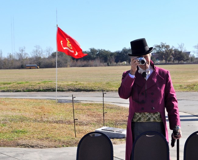 Man dressed in 1815 era clothes takes a photo with modern camera