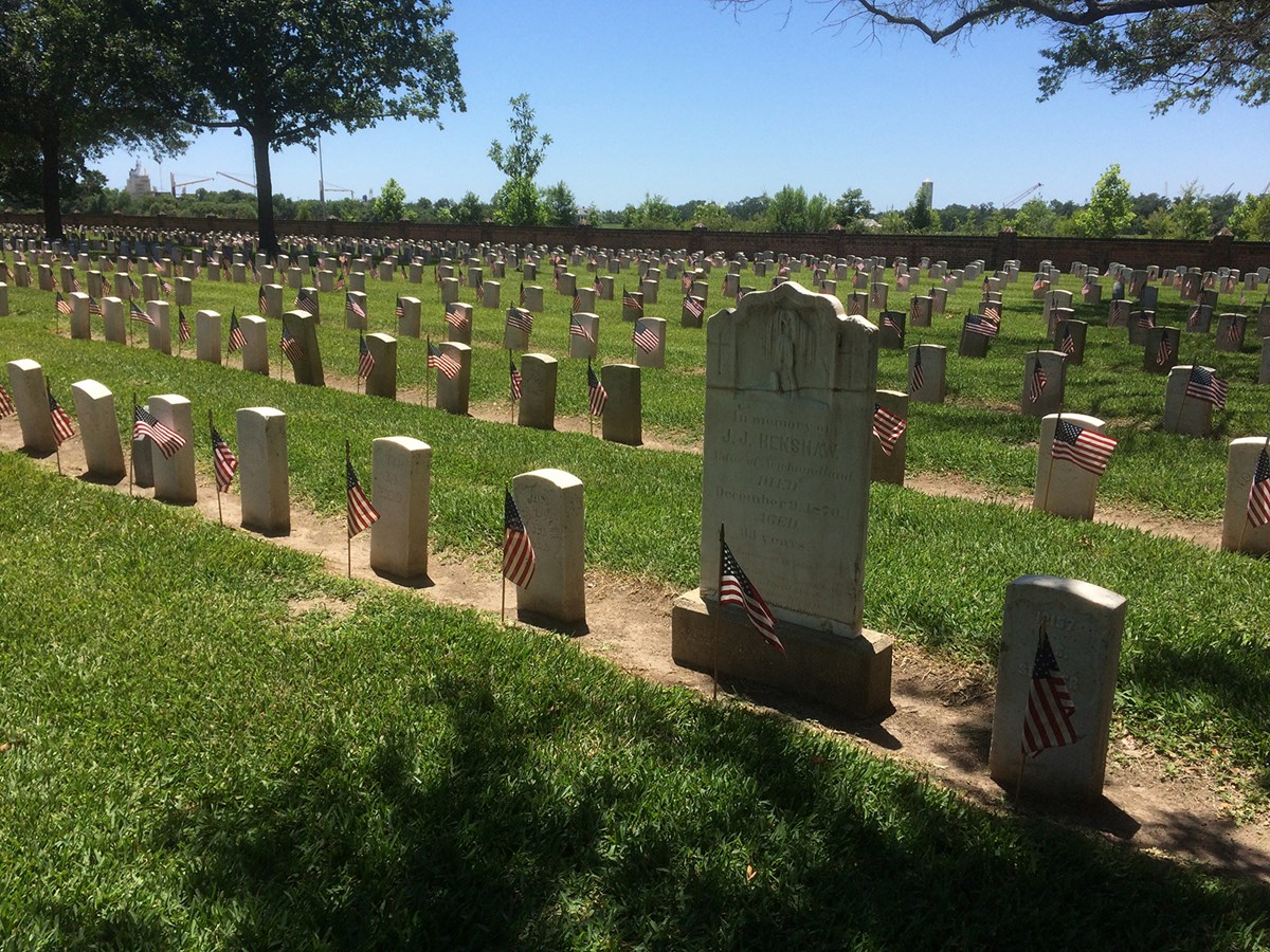 Rows of national cemetery headstones with an American flag in front of each Rows of national cemetery headstones with an American flag in front of each