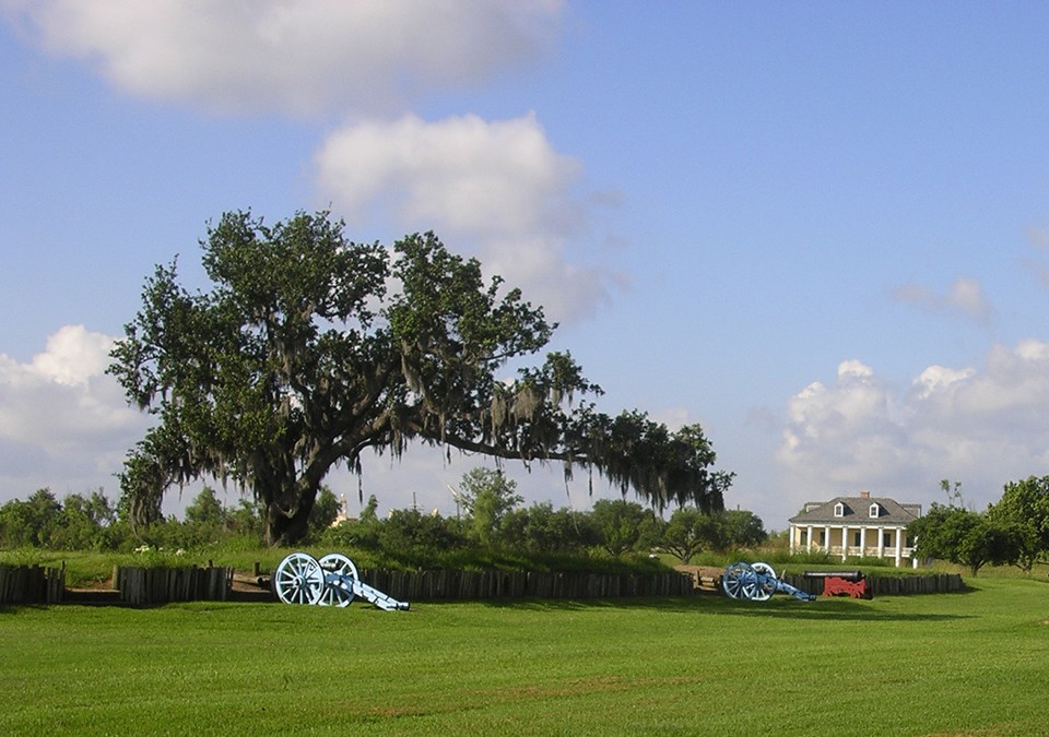 Cannons at a rampart with a historic home in background Cannons at a rampart with a historic home in background