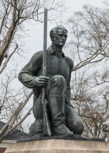 Statue of James (Jim) Bowie, by sculptor William M. McVey A color photo of a statue of Jim Bowie on one knee holding a long muzzled gun at his side, pointed at the sky.