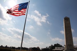 A large, fifteen star American flag from the War of 1812 flies beside the Chalmette Monument, a memorial obelisk