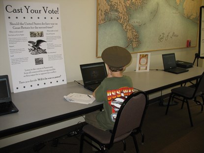 A child, seated at a park computer, watches an internet presentation on the causes of the War of 1812. A child, seated at a park computer, watches an internet presentation on the causes of the War of 1812.