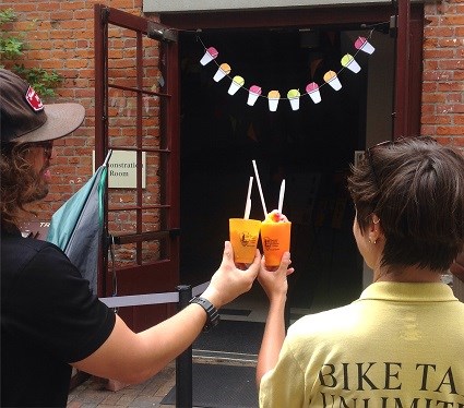 a man and a woman raise their shaved ice "snoball" cups together in a toast.