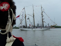 A reenactor in a French uniform of the War of 1812 watches a three masted sailing ship pass on the Mississippi River A reenactor in a French uniform of the War of 1812 watches a three masted sailing ship pass on the Mississippi River