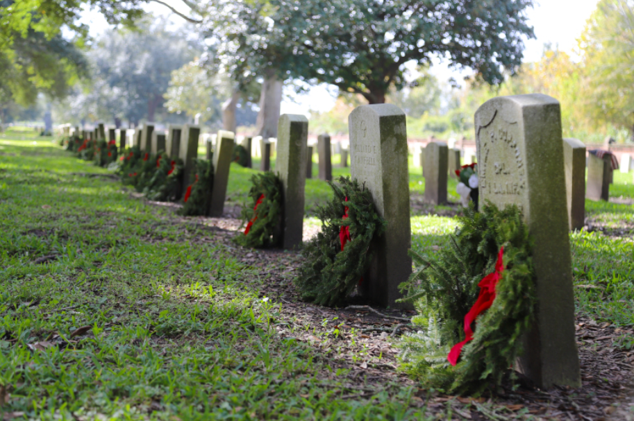 Wreaths laid in front of headstones in a cemetery.