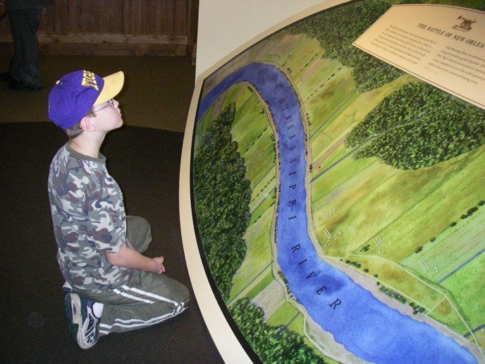 Image of young boy kneeling before a map of the New Orleans area
