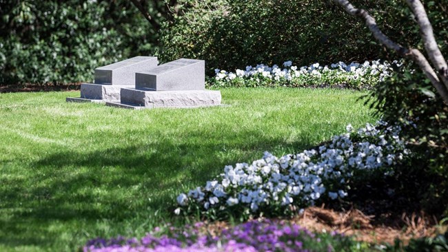 Two simple headstones in the center of a garden.