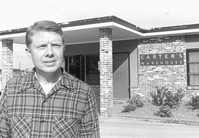 Jimmy Carter standing in front of Carter's Warehouse