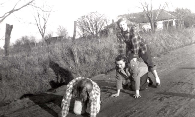 Ruth Carter takes the first leap over her friends Rosalynn Smith and Allene Timmerman in a game of leap frog in front of the Carter home.