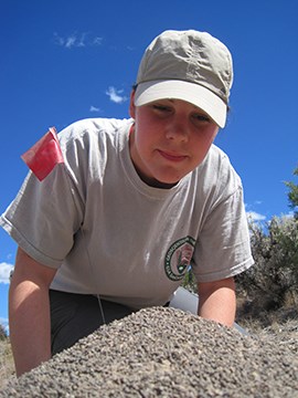 A Geo-Scientist-in-the-Park looks down at a pile of sediment