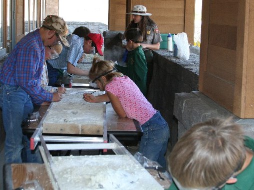 Teachers work with students in a simulated fossil dig.
