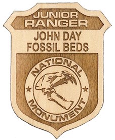The wooden junior ranger badge says Junior Park Ranger John Day Fossil Beds and has a fossil skull in the center.