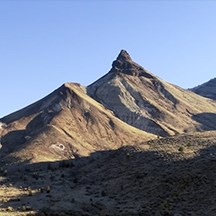 a hilly landscape with a sharp tipped mountain