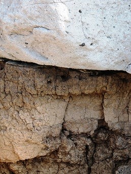 Image of different types of rock formation layers. Top layer is lighter in color and more smooth. Bottom layer is varying shades of brown with more cracks and texture.