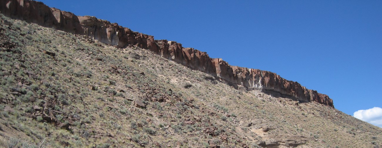 A large, rocky slope against a blue sky.