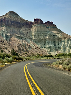 Cathedral Rock rises prominently, displaying dramatic layers of pale green, tan, and reddish-brown sedimentary rock. The sky above is mostly clear with some smoky haze, adding contrast to the striking colors and textures of the landscape