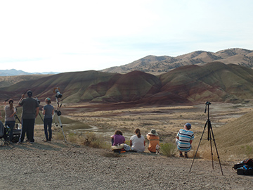 Seven people line up in front of the Painted Hills to view the solar eclipse.