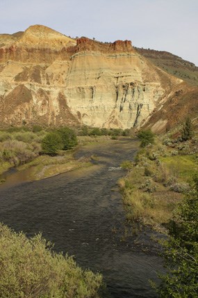 A river is in the foreground with a colorful cliff in the background. A river is in the foreground with a colorful cliff in the background.