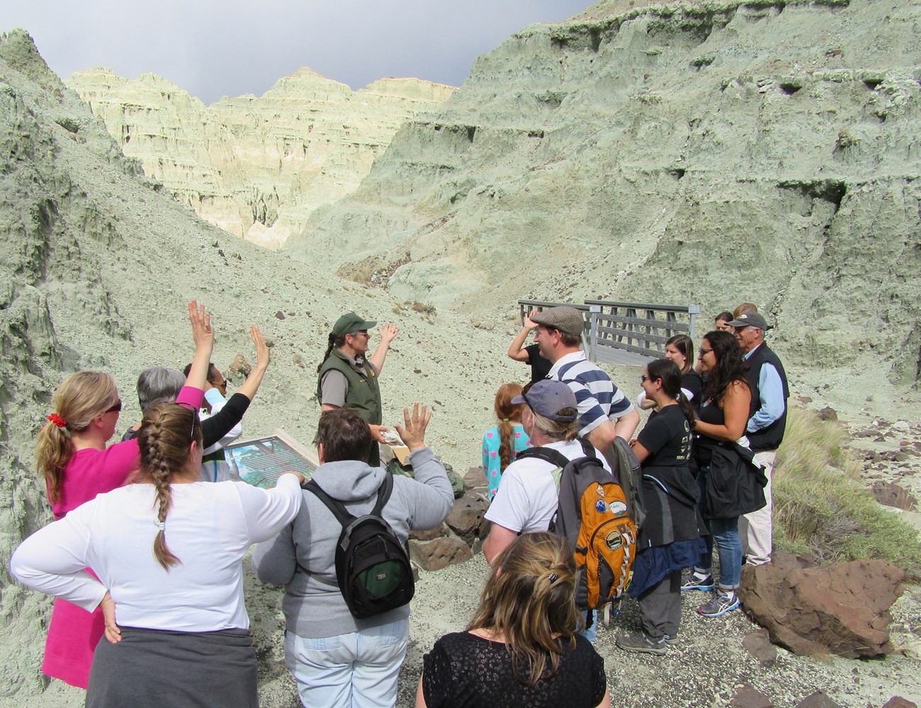 A Ranger Leads a hike into Blue Basin through the blue canyon on the Island in Time Trail. Several people gather around her and a couple have their hand raised.