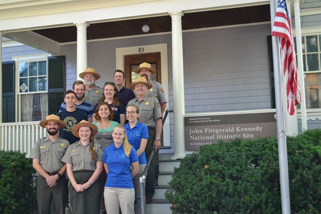 Color photo of JFK NHS staff on front steps of house.