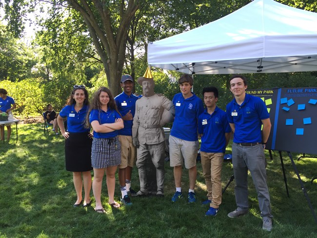 A group of Stewards wearing their blue uniform polos pose for a photo outdoors.