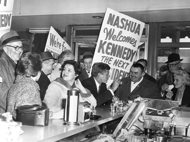 JFK seated at a lunch counter with a group of supporters