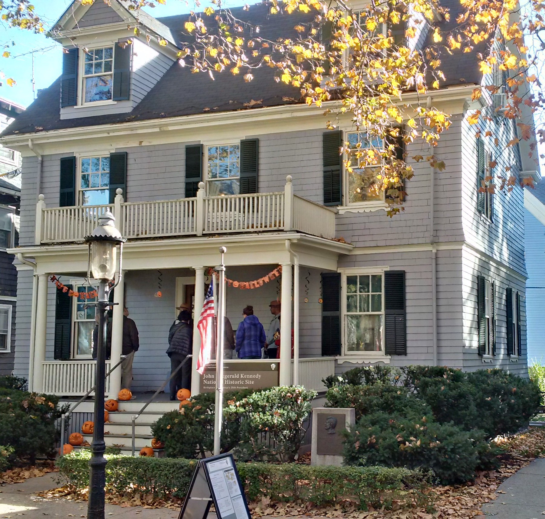 JFK Birthplace on Halloween. Pumpkins line the stairs to the porch. JOFI with Visitors and Pumpkins on the porch