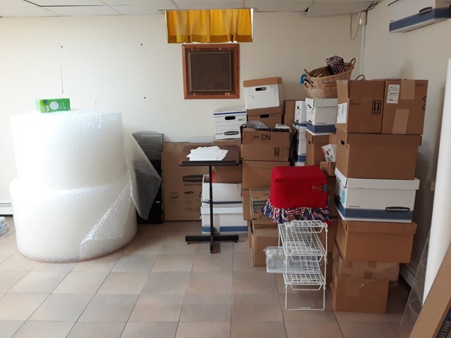 A stack of boxes and packing supplies sit in the corner of a room