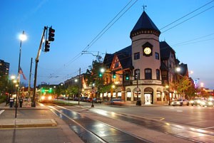 Coolidge Corner at night; buildings are lit, the moon is visable