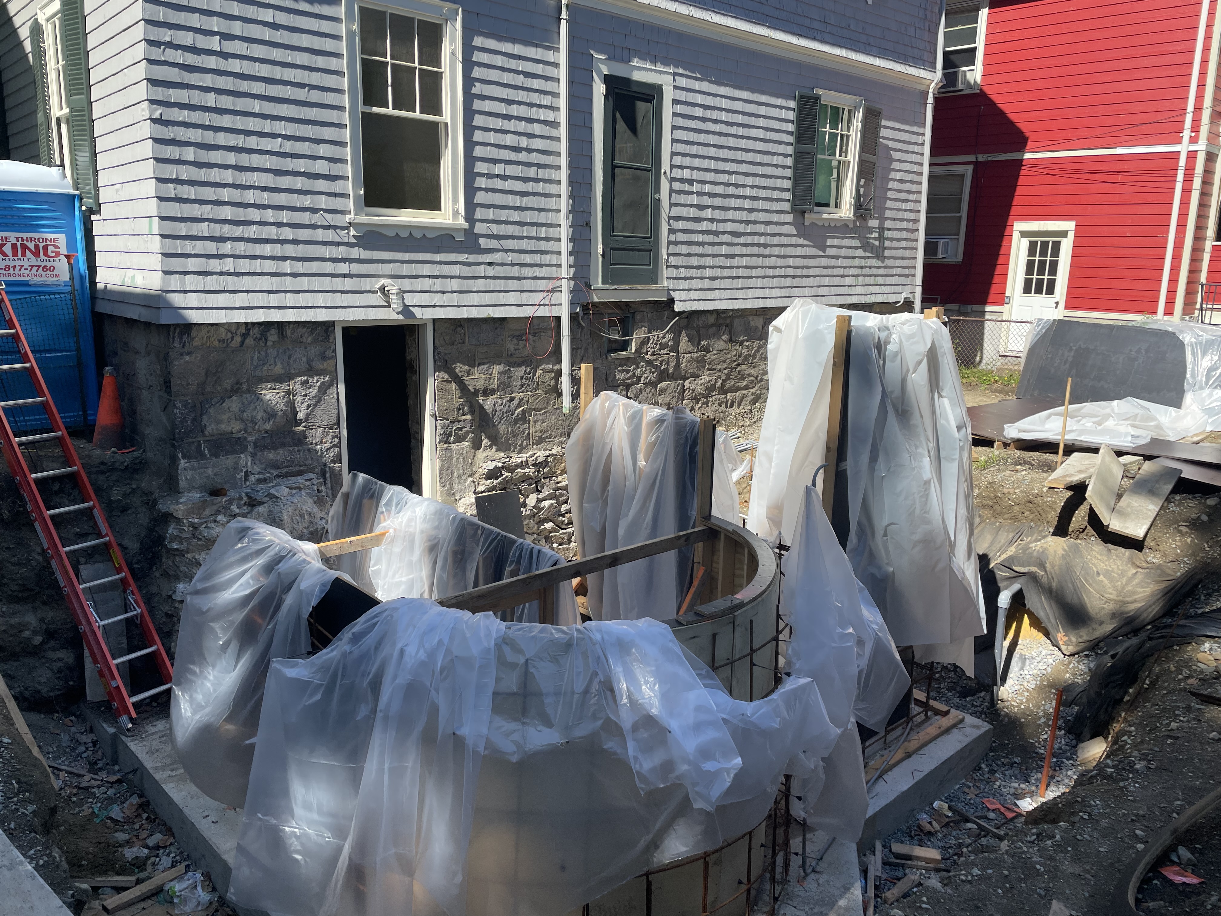 A large hole in the backyard at JFK NHS with beams and construction materials.